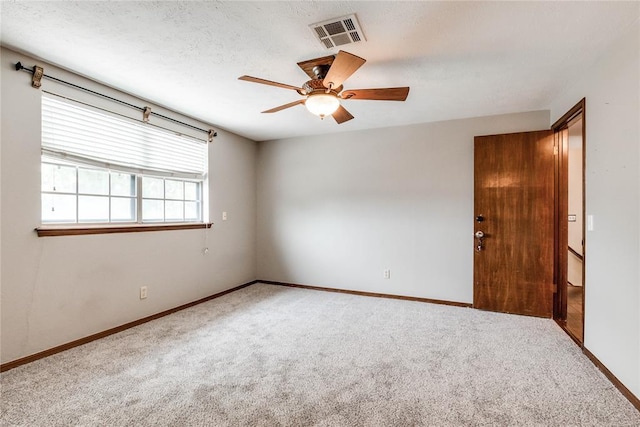 carpeted empty room featuring baseboards, ceiling fan, and visible vents
