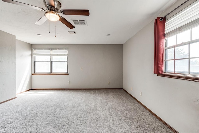 empty room with a healthy amount of sunlight, a ceiling fan, carpet flooring, and visible vents