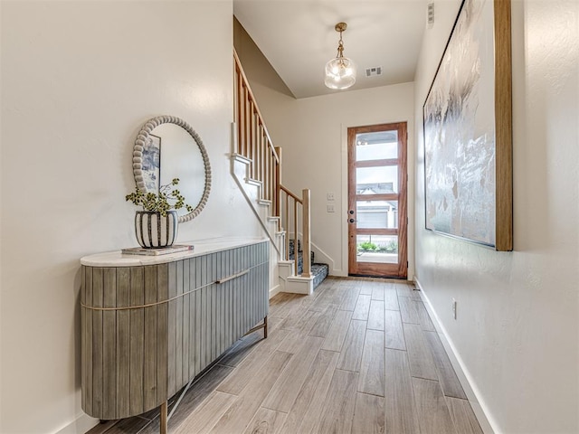 entrance foyer with baseboards, visible vents, stairway, and light wood-type flooring