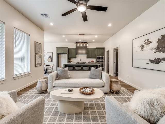 living room featuring a ceiling fan, baseboards, recessed lighting, wood finished floors, and visible vents