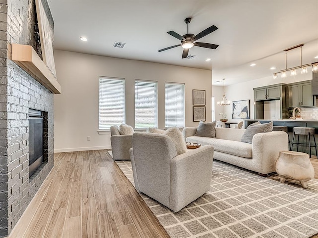 living area with visible vents, a fireplace, ceiling fan, recessed lighting, and light wood-style flooring