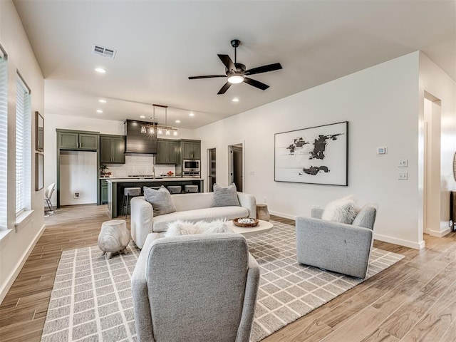 living room with visible vents, baseboards, recessed lighting, a ceiling fan, and light wood finished floors