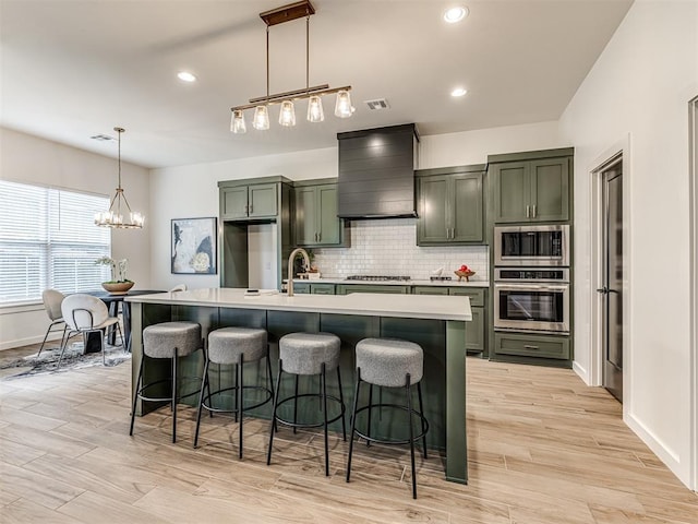 kitchen featuring decorative backsplash, appliances with stainless steel finishes, light countertops, premium range hood, and green cabinets