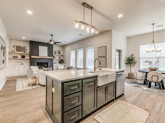 kitchen featuring visible vents, stainless steel dishwasher, light wood-type flooring, a sink, and ceiling fan with notable chandelier
