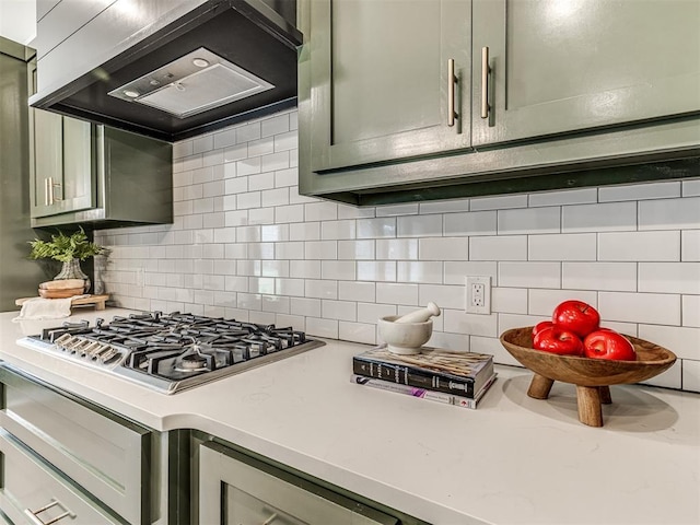 kitchen with stainless steel gas stovetop, light countertops, tasteful backsplash, and custom range hood
