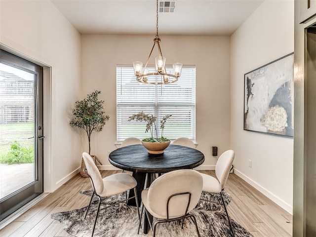 dining space with a healthy amount of sunlight, light wood-style flooring, a chandelier, and visible vents