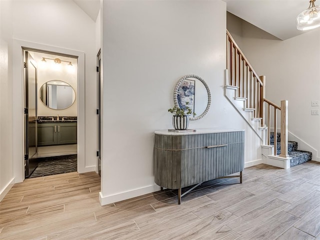 interior space with stairs, baseboards, a sink, and wood tiled floor