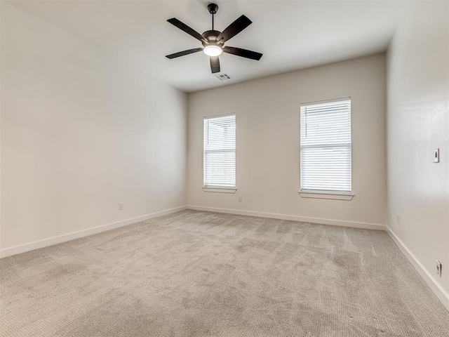 unfurnished room with light colored carpet, baseboards, visible vents, and ceiling fan