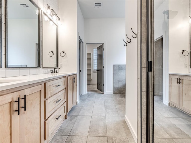 full bathroom with double vanity, tile patterned floors, baseboards, and visible vents