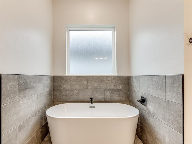 bathroom with tile walls and a soaking tub