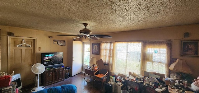 living area featuring dark wood-style flooring, a textured ceiling, a wealth of natural light, and ceiling fan