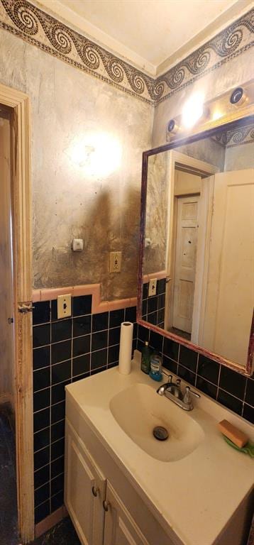 bathroom with wallpapered walls, a wainscoted wall, vanity, and tile walls