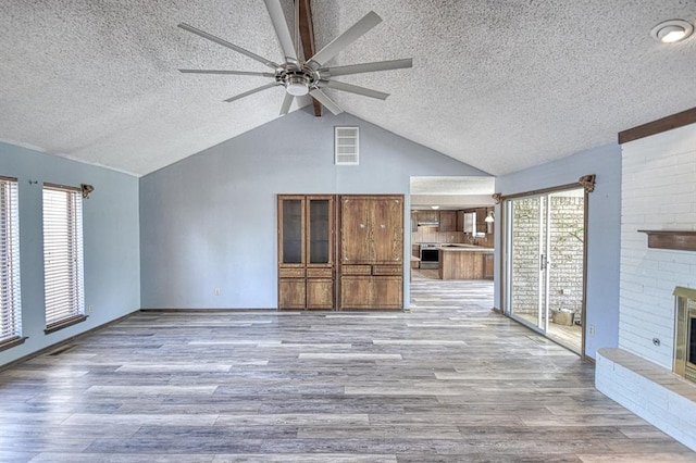 204 Sequoia Park Dr, Yukon, OK 73099 - unfurnished living room featuring wood finished floors, a ceiling fan, a fireplace, a textured ceiling, and lofted ceiling