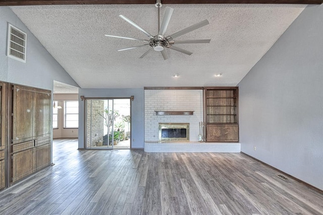 204 Sequoia Park Dr, Yukon, OK 73099 - unfurnished living room featuring wood finished floors, a textured ceiling, visible vents, a brick fireplace, and a ceiling fan