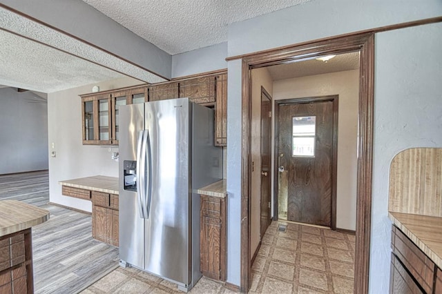 204 Sequoia Park Dr, Yukon, OK 73099 - kitchen with light countertops, a textured ceiling, brown cabinetry, and stainless steel refrigerator with ice dispenser
