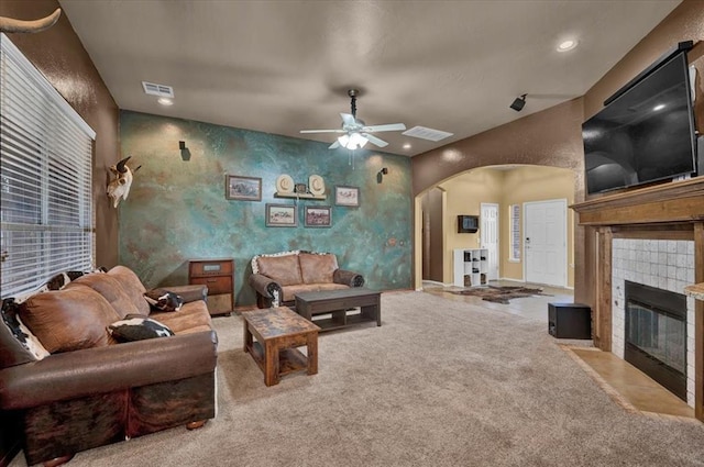 carpeted living room featuring a fireplace, arched walkways, a ceiling fan, recessed lighting, and visible vents