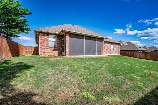 rear view of property featuring an attached garage, a yard, and brick siding