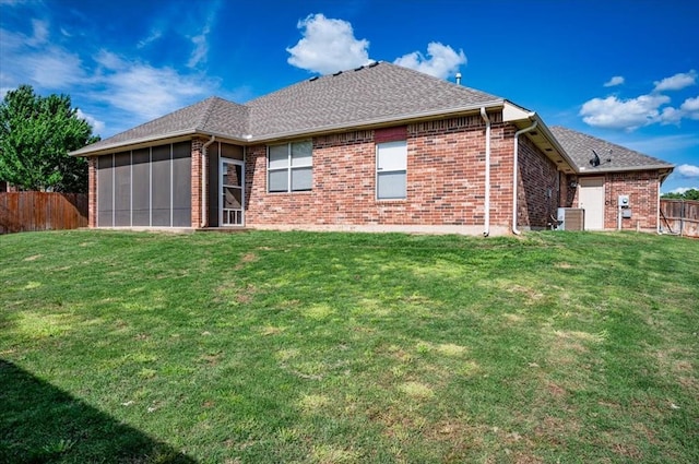 back of property with brick siding, fence, and a yard