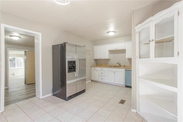 556 SW 52nd St, Oklahoma City, OK 73109 - kitchen with a sink, light countertops, white cabinets, light tile patterned floors, and stainless steel appliances