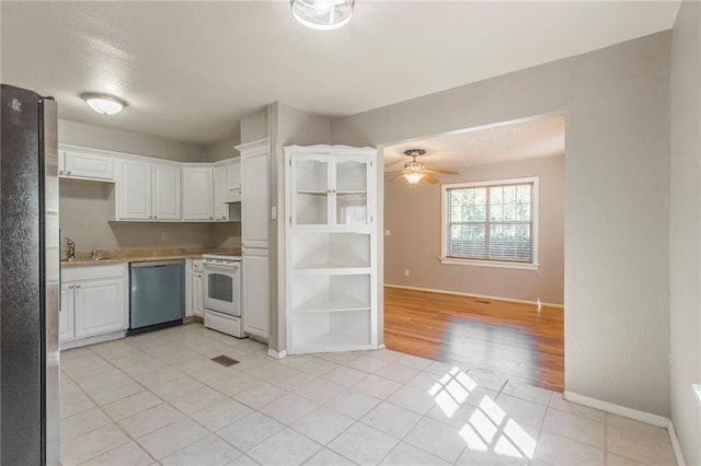 556 SW 52nd St, Oklahoma City, OK 73109 - kitchen featuring a ceiling fan, appliances with stainless steel finishes, light tile patterned floors, baseboards, and white cabinets