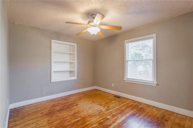 556 SW 52nd St, Oklahoma City, OK 73109 - spare room featuring baseboards, a textured ceiling, built in features, and hardwood / wood-style flooring