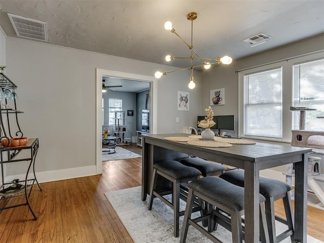 2247 NW 35th St, Oklahoma City, OK 73112 - dining room with baseboards, visible vents, wood finished floors, and ceiling fan with notable chandelier