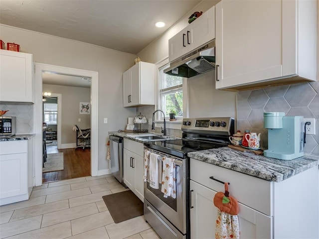 2247 NW 35th St, Oklahoma City, OK 73112 - kitchen featuring appliances with stainless steel finishes, tasteful backsplash, light stone counters, under cabinet range hood, and white cabinetry