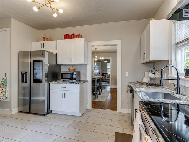 2247 NW 35th St, Oklahoma City, OK 73112 - kitchen featuring light stone countertops, wall chimney exhaust hood, a sink, a notable chandelier, and stainless steel appliances