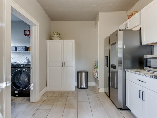 2247 NW 35th St, Oklahoma City, OK 73112 - kitchen with washer / clothes dryer, appliances with stainless steel finishes, white cabinetry, light stone counters, and light tile patterned flooring