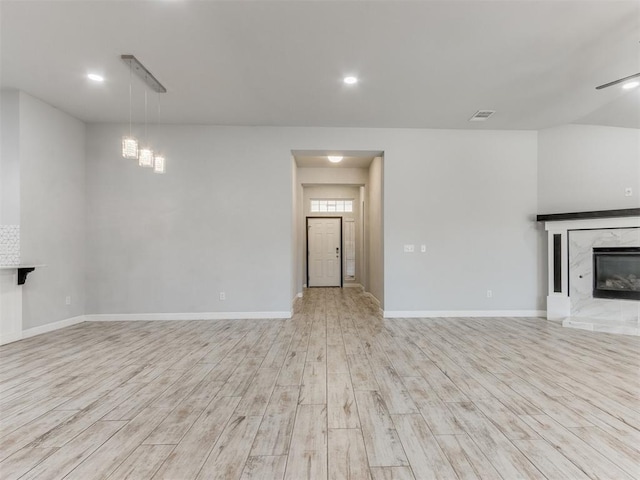 unfurnished living room featuring baseboards, visible vents, wood finished floors, and a fireplace