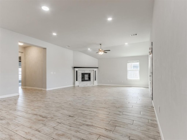 unfurnished living room featuring wood tiled floor, a ceiling fan, visible vents, vaulted ceiling, and baseboards