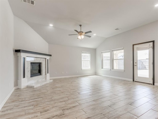 unfurnished living room with ceiling fan, vaulted ceiling, light wood-style flooring, and visible vents
