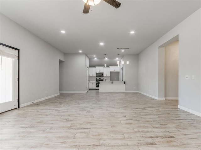 unfurnished living room with baseboards, ceiling fan, recessed lighting, and light wood-style flooring