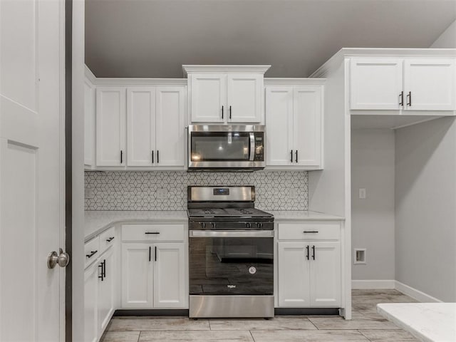 kitchen with wood tiled floor, appliances with stainless steel finishes, white cabinets, and tasteful backsplash