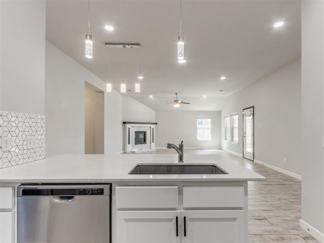 kitchen with a ceiling fan, dishwasher, a sink, open floor plan, and light wood-style flooring