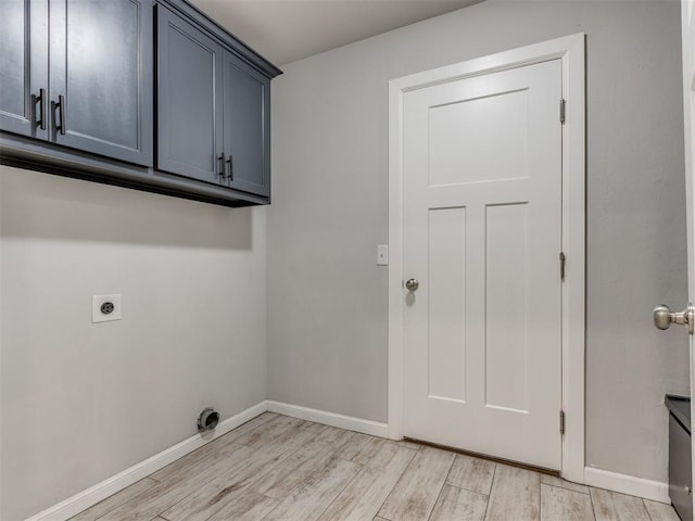 washroom with cabinet space, electric dryer hookup, baseboards, and light wood-type flooring