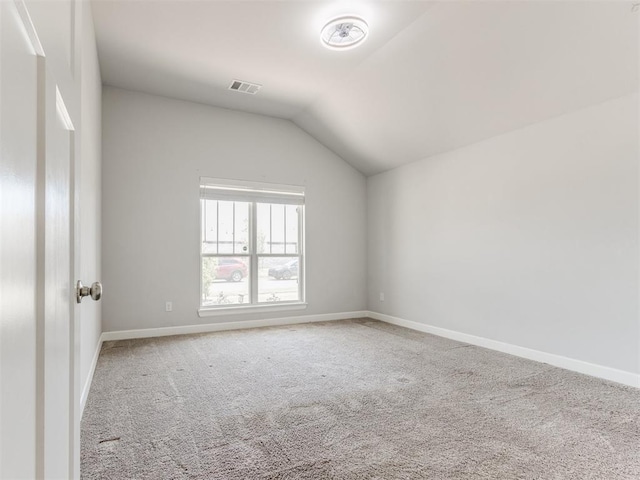 empty room with baseboards, vaulted ceiling, carpet flooring, and visible vents