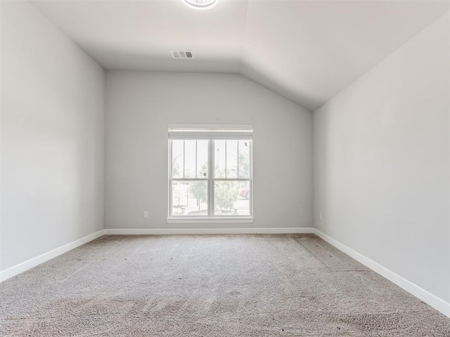 spare room featuring carpet flooring, baseboards, visible vents, and vaulted ceiling