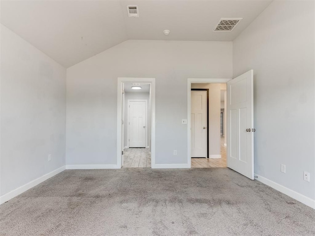 unfurnished bedroom featuring baseboards, visible vents, lofted ceiling, and light colored carpet