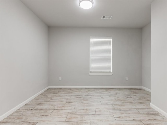 spare room featuring baseboards, visible vents, and light wood-style flooring