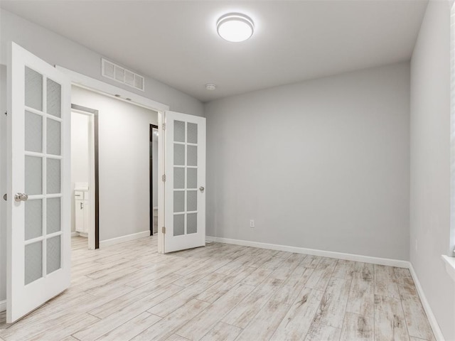 unfurnished room with baseboards, visible vents, french doors, and wood finished floors