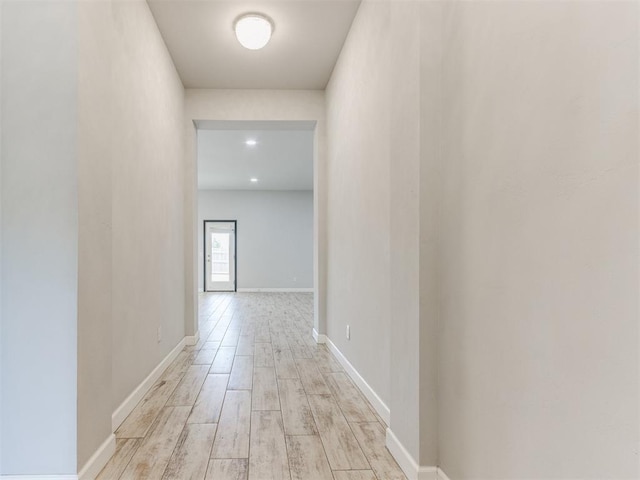 hallway featuring baseboards and light wood-style floors