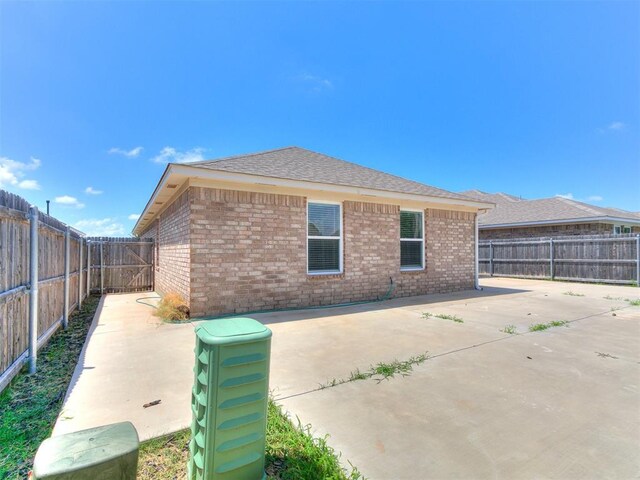 12929 NW 4th St, Yukon, OK 73099 - back of house with a patio area, a fenced backyard, brick siding, and a shingled roof