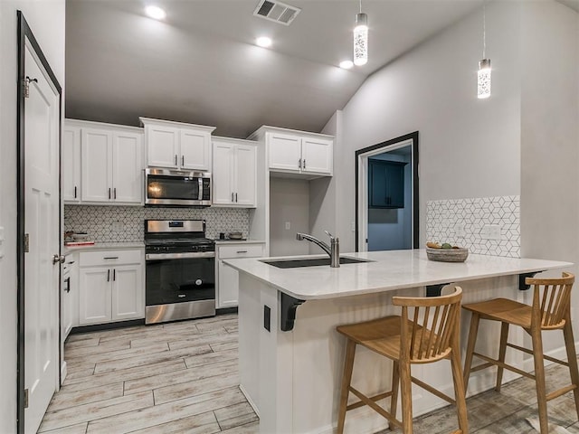 12929 NW 4th St, Yukon, OK 73099 - kitchen featuring stainless steel appliances, a peninsula, vaulted ceiling, white cabinetry, and backsplash