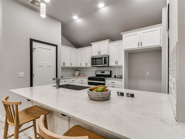 12929 NW 4th St, Yukon, OK 73099 - kitchen featuring appliances with stainless steel finishes, white cabinets, tasteful backsplash, lofted ceiling, and light stone counters