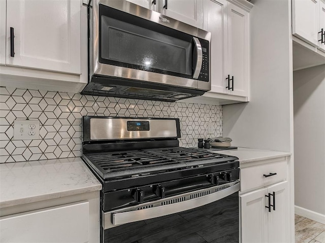 12929 NW 4th St, Yukon, OK 73099 - kitchen with appliances with stainless steel finishes, white cabinetry, tasteful backsplash, and light stone countertops