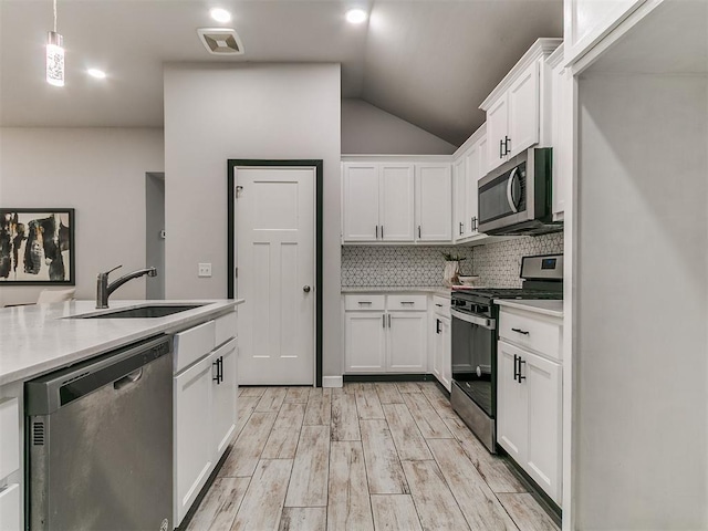 12929 NW 4th St, Yukon, OK 73099 - kitchen featuring appliances with stainless steel finishes, light countertops, white cabinets, tasteful backsplash, and lofted ceiling