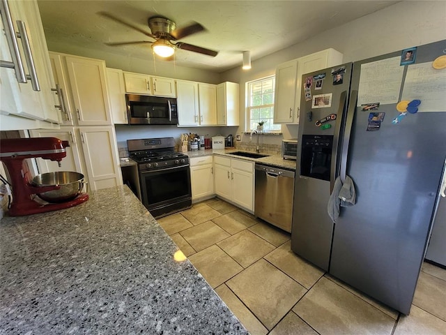kitchen with a ceiling fan, light stone countertops, white cabinets, a sink, and stainless steel appliances