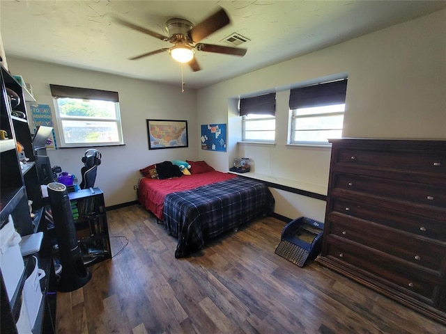 bedroom with baseboards, ceiling fan, wood finished floors, and visible vents