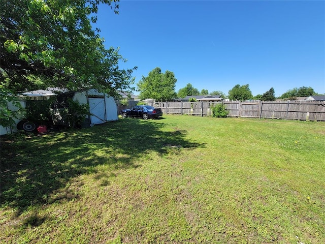 view of yard with a storage unit, a fenced backyard, and an outdoor structure